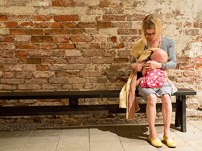 woman carrying baby and sitting on bench thumbnail
