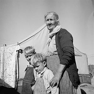 grayscale photography of woman beside two boys thumbnail