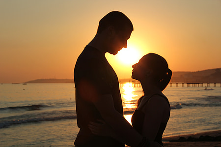 silhouette photo of man and woman standing near beach thumbnail