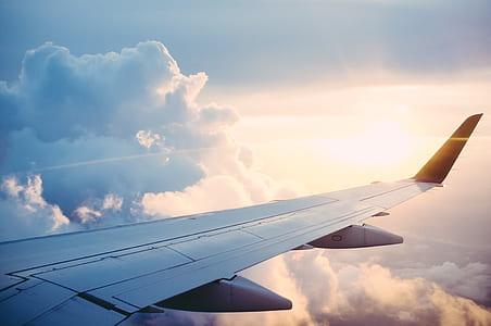 gray airplane on top of the clouds at sunrise thumbnail