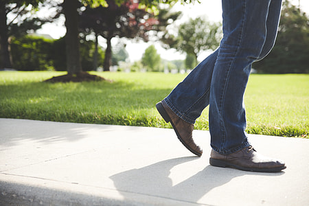 person walking on sidewalk beside grass field thumbnail
