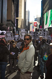 man standing near people gathering near building thumbnail