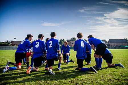 group of man wearing jersey shirt kneeling on green grassfield during daytime thumbnail