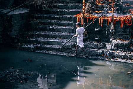 man standing holding spare beside water thumbnail