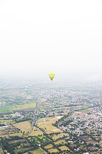 aerial photography of yellow and green striped hot-air balloon over town thumbnail