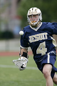 Man Holding Lacrosse Stick Running on Field during Daytime thumbnail