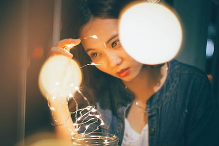 Woman In Blue Denim Jacket Holding String Lights thumbnail