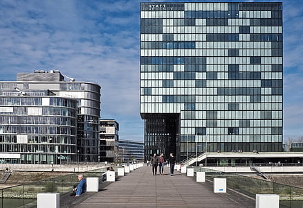 three person walking near gray concrete building thumbnail