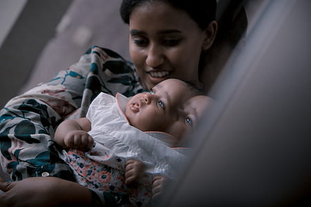 woman carrying baby in white tops leaning on wall thumbnail