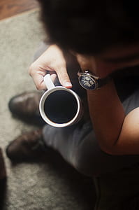 man holding white mug near gray rug thumbnail