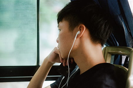 man in black top inside car while using white earphones thumbnail