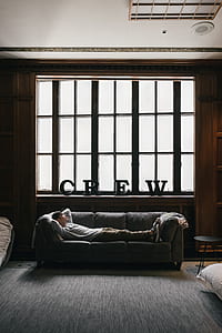 man lying on sofa near window during daytime thumbnail