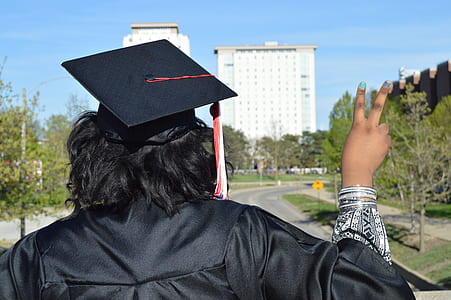 man in black graduation gown making a peace sign thumbnail