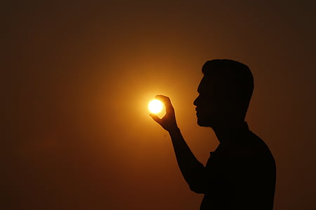 forced perspective photo of silhouette of man holding sun thumbnail