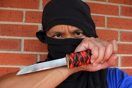 person holding knife beside brown brick wall thumbnail