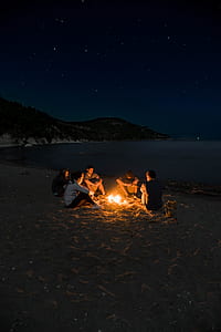 people sitting near bonfire near seashore during nighttime thumbnail