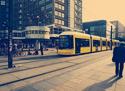 Selective Color Photography of Yellow Train Near Concrete Buildings thumbnail