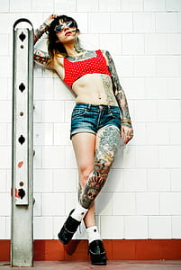 woman wearing red crop top and blue denim short shorts leaning on gray ladder thumbnail