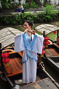 woman playing flute while standing on boat thumbnail