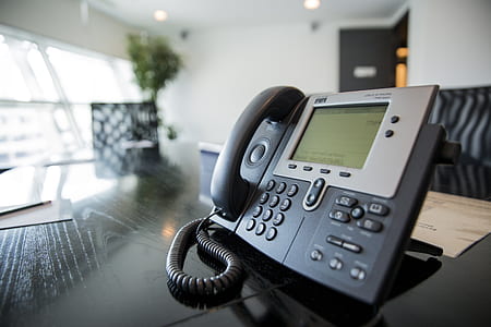black and grey IP phone on black desk thumbnail