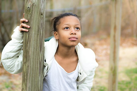 boy in white hoodie holding a tree trunk while looking upwawrd thumbnail