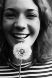 grayscale photo of woman holding dandelion flower thumbnail