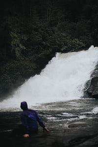 person wearing purple jacket looking at waterfalls thumbnail