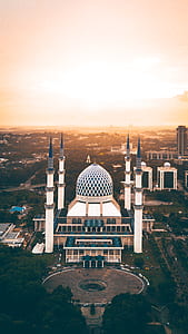 white concrete mosque surrounded with buildings thumbnail