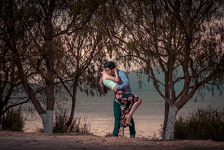 couple kissing near trees during daytime thumbnail