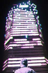 man staring up to the high rise building during nighttime thumbnail