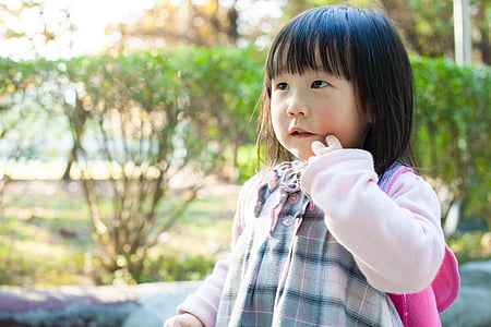 girl standing near green leafed plants thumbnail