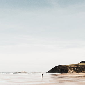 person near ocean water and brown rock formation during daytime thumbnail