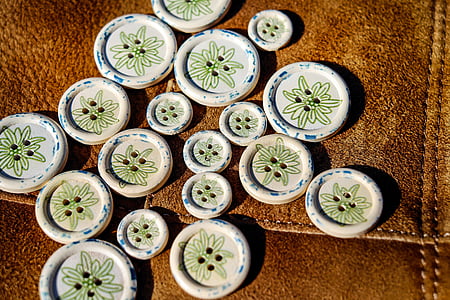 round white-and-green clothes button lot on brown textile thumbnail