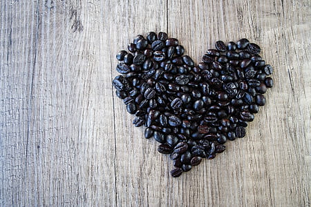 heart-shaped black coffee beans on brown wooden surface thumbnail