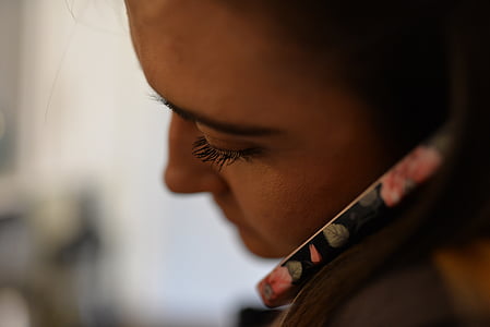 selective focus photography of woman putting phone on her left ear thumbnail