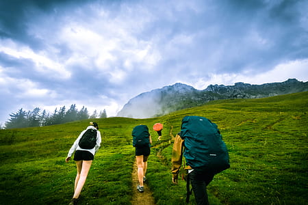four person hiking on mountain under cloudy sky thumbnail