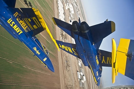blue and yellow jet plane hovering on grass field thumbnail
