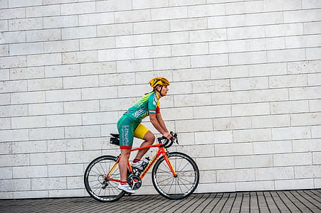 man riding road bike beside concrete wall thumbnail