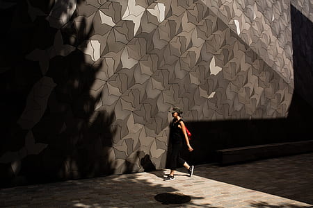 woman walking near brown wall during daytime photo thumbnail
