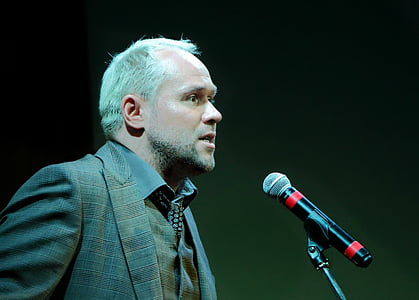 man standing beside black microphone inside room thumbnail