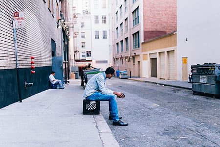 man sitting on black stool during daytime thumbnail