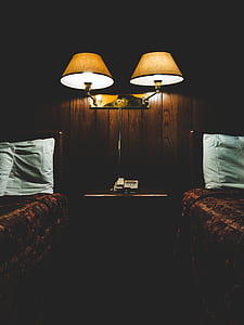 turned-on wall lamp between beds thumbnail
