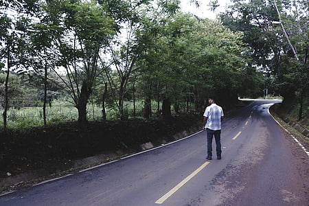 man in white shirt and black bottoms standing on road thumbnail