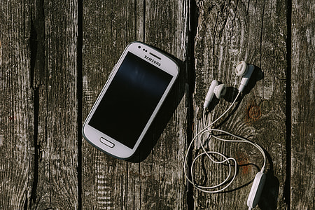 White smartphone with various items on a wooden background thumbnail