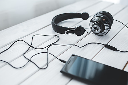 photo of black corded headphones beside smartphone on table thumbnail