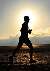 silhouette photo of man walking near body of water under cloudy sky during daytime thumbnail