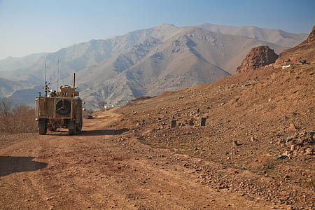 brown armored vehicle on dirt road during daytime thumbnail
