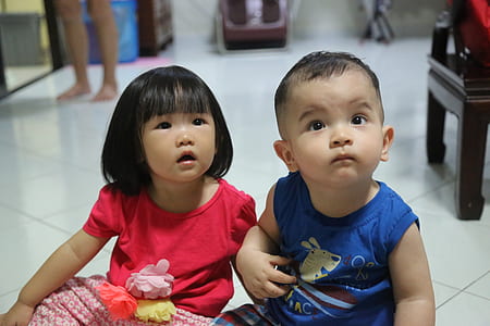 boy and girl sitting on white ceramic flooring thumbnail