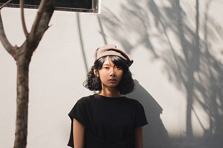 woman wearing black crew-neck t-shirt standing near white painted wall thumbnail