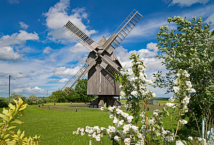 brown wooden windmill in the middle of green grass field under cloudy blue sky during daytime thumbnail